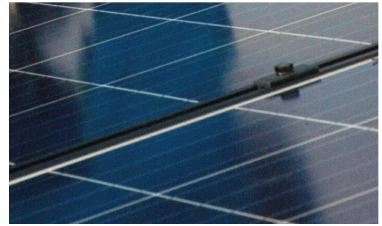 Close-up of solar panel surface showing blue photovoltaic cells and white grid lines.
