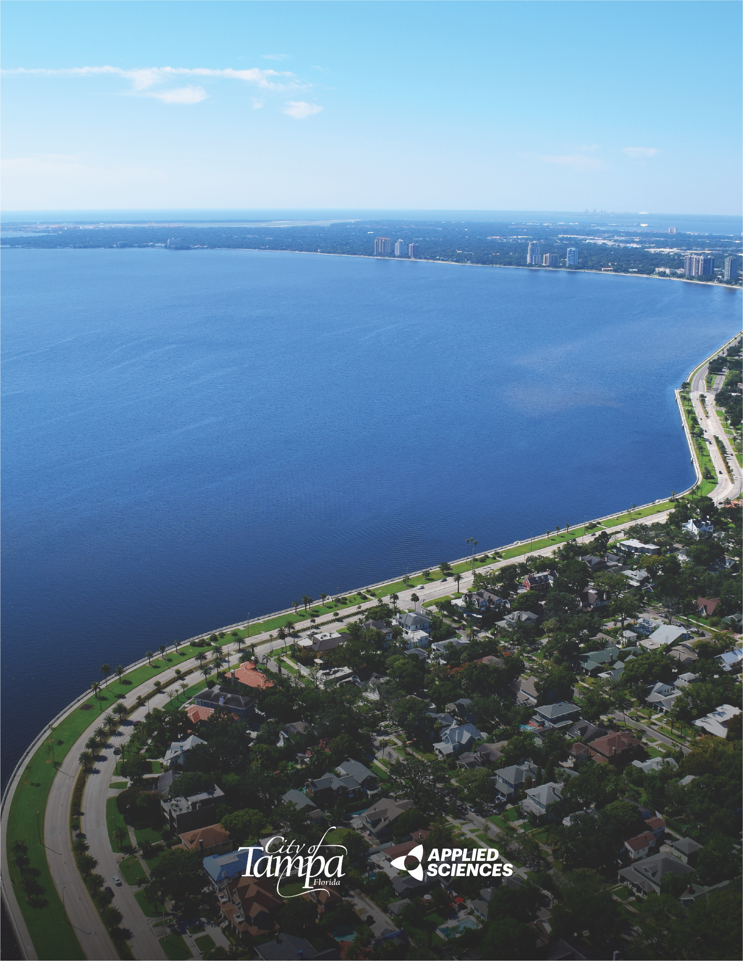 Aerial view of Tampa's waterfront, showcasing the cityscape and shoreline with blue skies above.