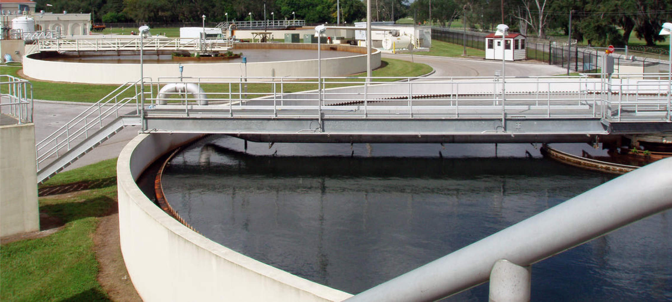 Overview of a water treatment facility featuring circular tanks and walkways for wastewater processing.
