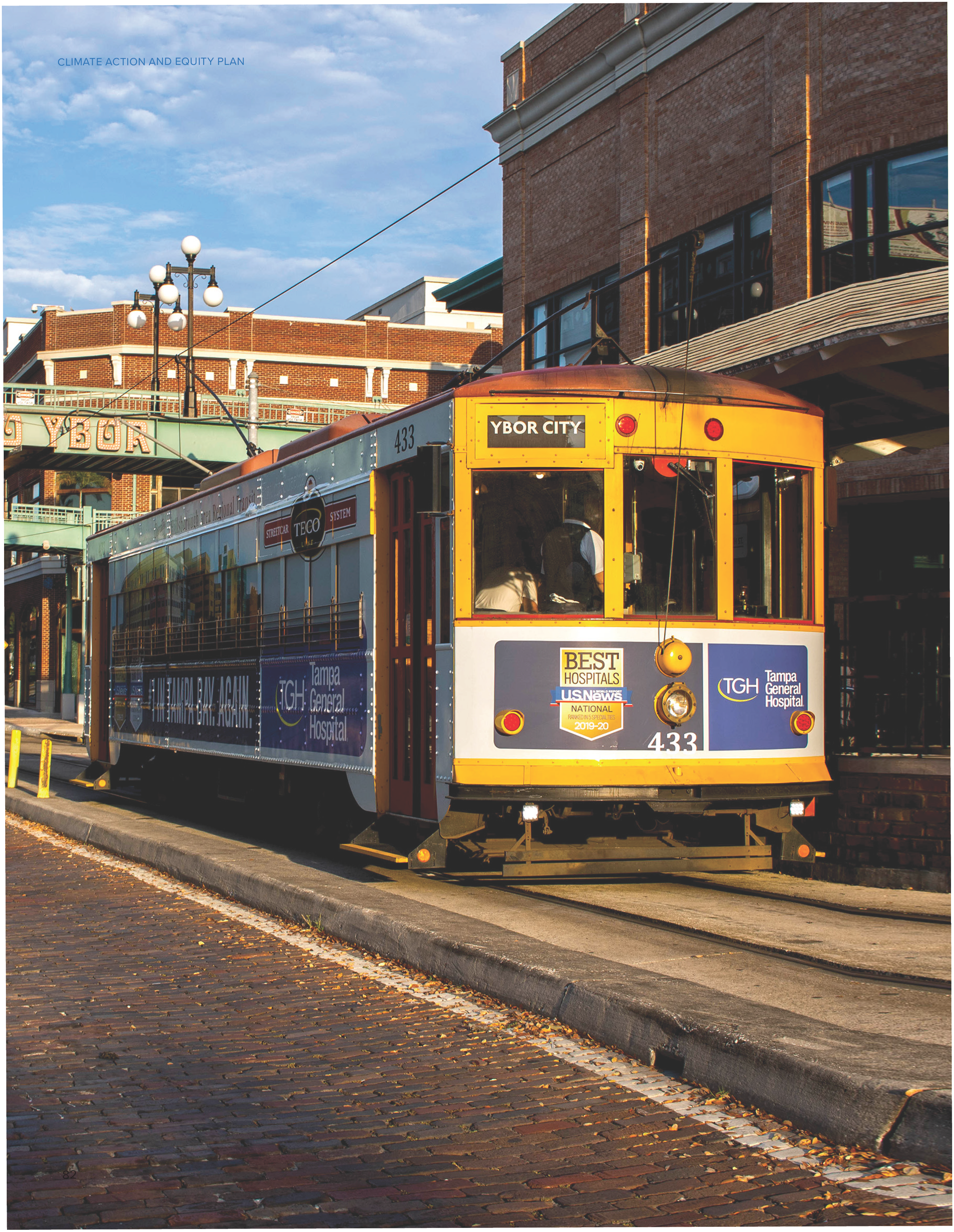A vintage streetcar at a station in Ybor City, Tampa, with advertisements on the side.