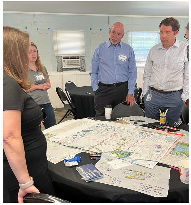 Group of professionals discussing a map at a round table in a meeting room.
