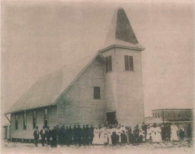 Historic black-and-white photo of a church with a group of people gathered in front.