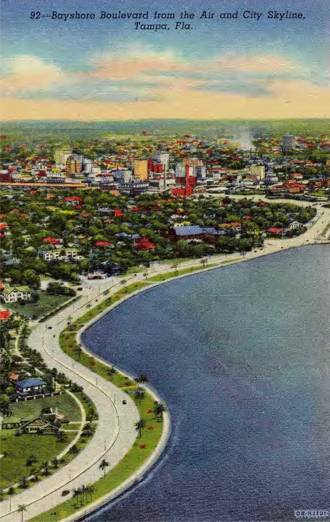 Aerial view of Bayshore Boulevard and city skyline in Tampa, Florida, featuring water and greenery.