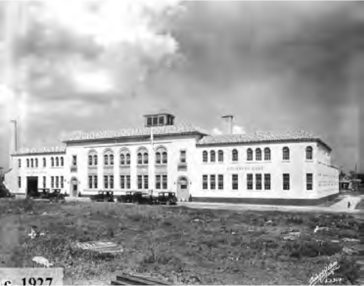 Historic black and white photo of a large, two-story school building from 1927, surrounded by a grassy area.