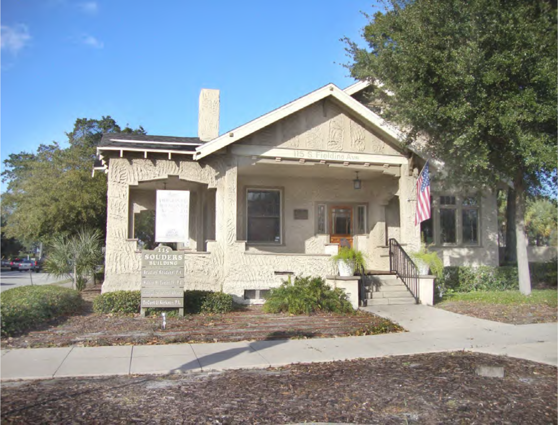Historic building with decorative stone facade, front steps, and American flag, featuring a sign for the Soldiers' Building.