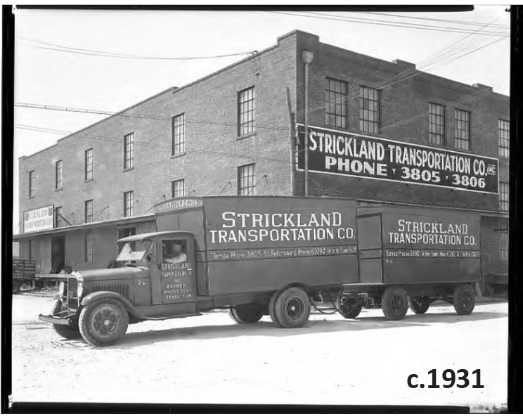 Historical black and white photo of a Strickland Transportation Co. truck parked in front of a brick warehouse, circa 1931.