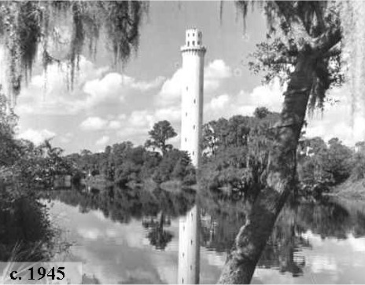 Black and white image of a tall tower reflecting in a calm river surrounded by trees, taken around 1945.