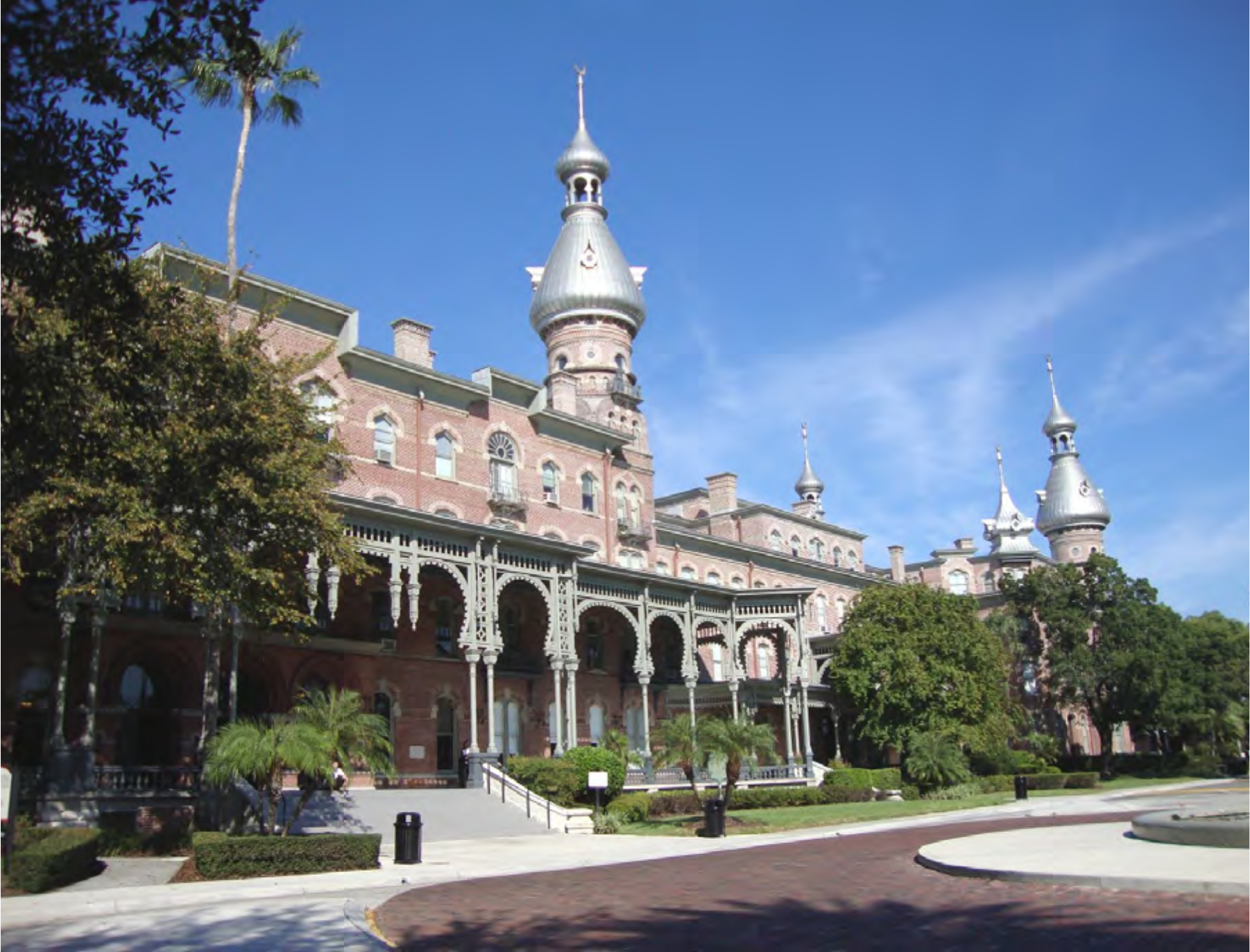Historic building with towers and greenery under a clear blue sky.