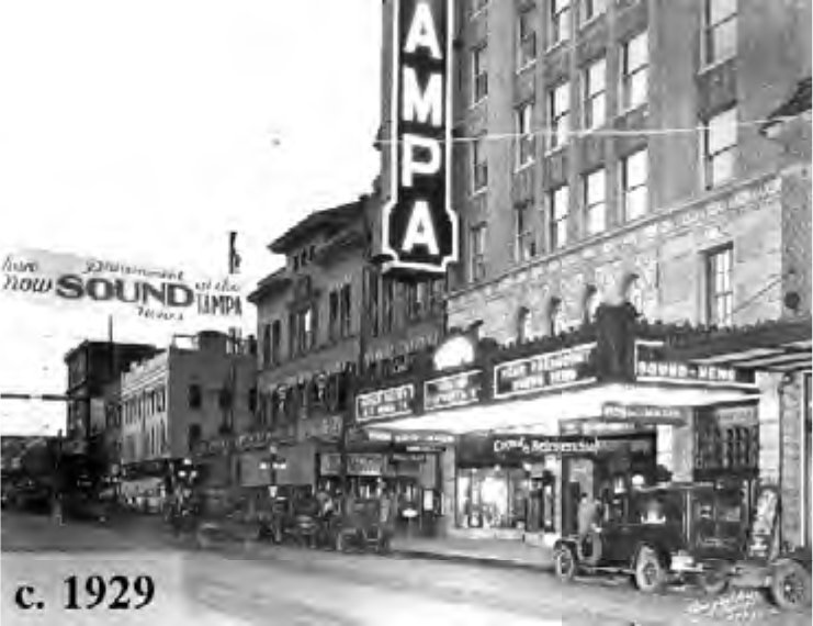 Historical black and white image of Tampa's movie theater district in 1929, featuring vintage cars and a bustling street scene.