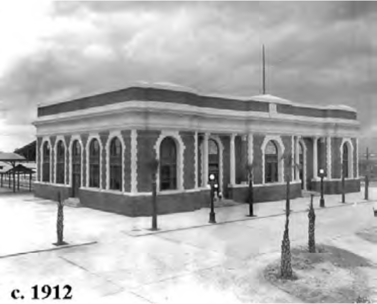 Historic building from around 1912, featuring arched windows and a decorative façade, set in a public space with lampposts.