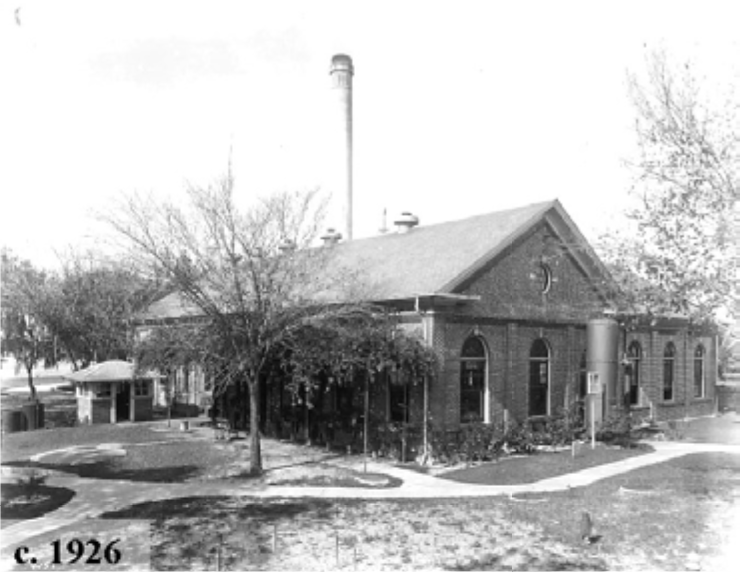 Historic brick building surrounded by trees, featuring a tall chimney, taken around 1926.
