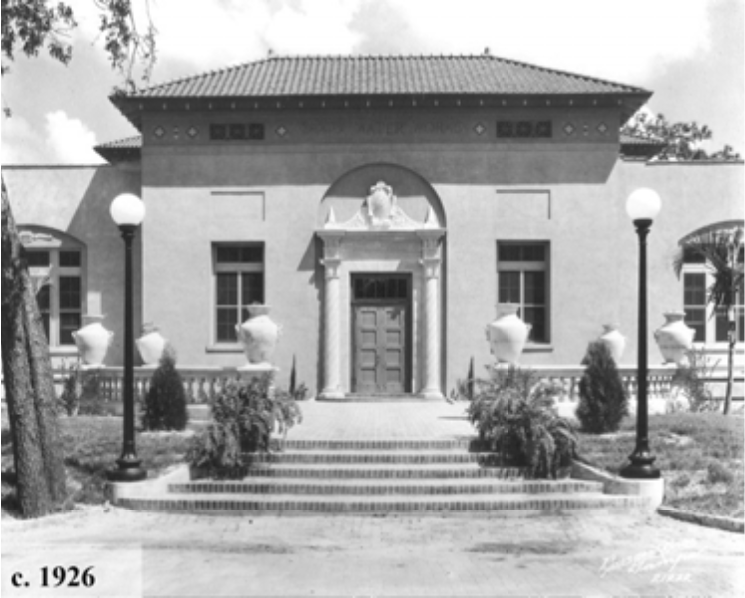 Historic building façade from c. 1926, featuring decorative architecture, potted plants, and lampposts.