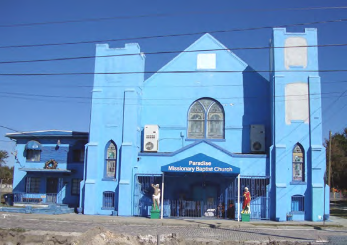 A blue building with towers, labeled 'Paradise Missionary Baptist Church', featuring decorative elements and a gated entrance.