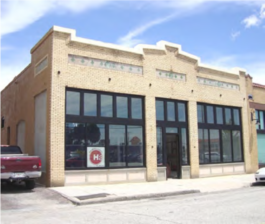 A beige brick building with large windows and a distinct architectural design, displaying a logo on the front.