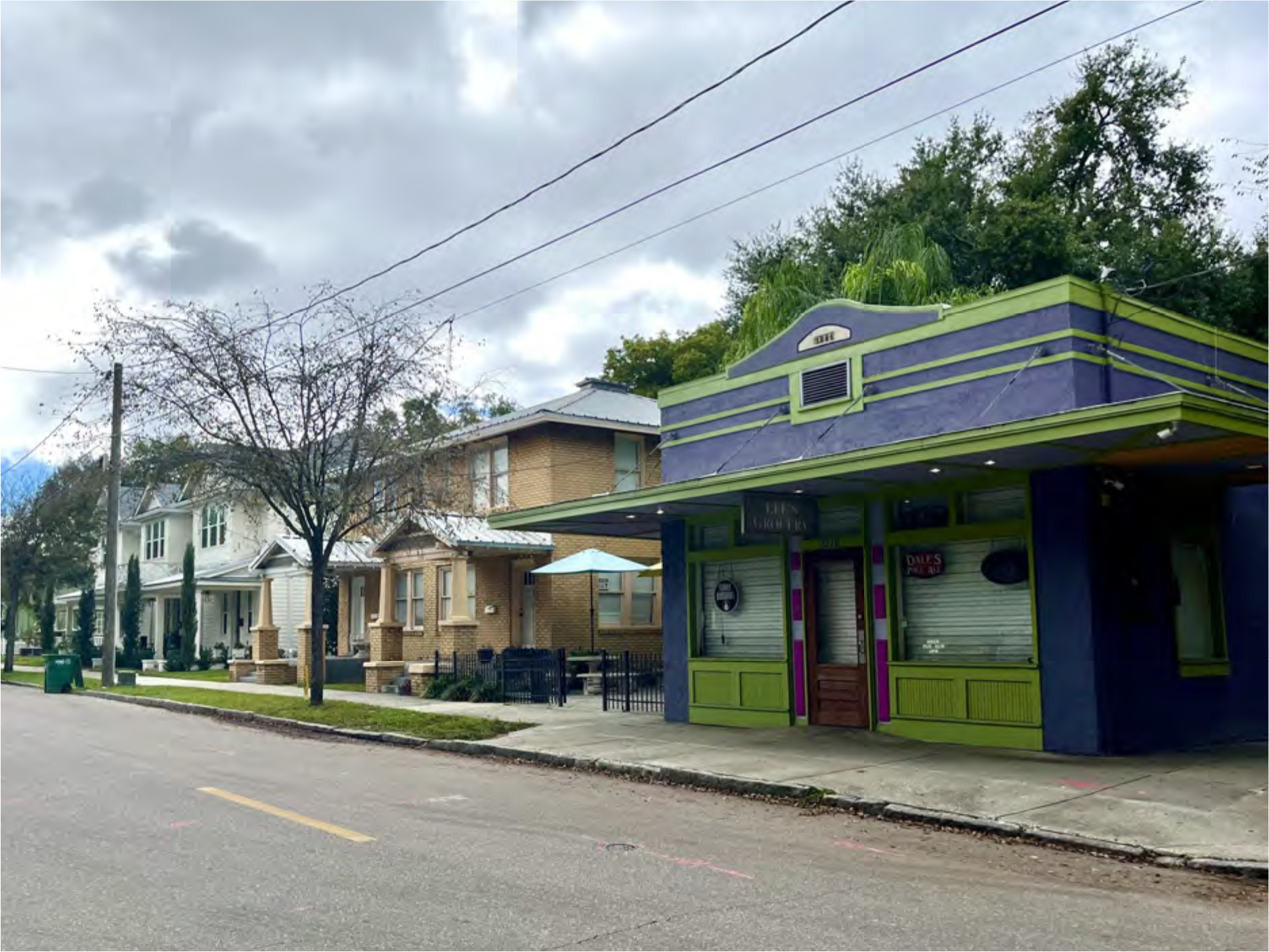 Street view featuring a colorful shopfront with green and purple accents beside residential houses.
