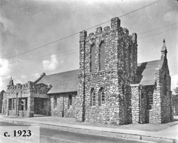 Historic stone church building from circa 1923, featuring a tall tower and detailed architectural elements.