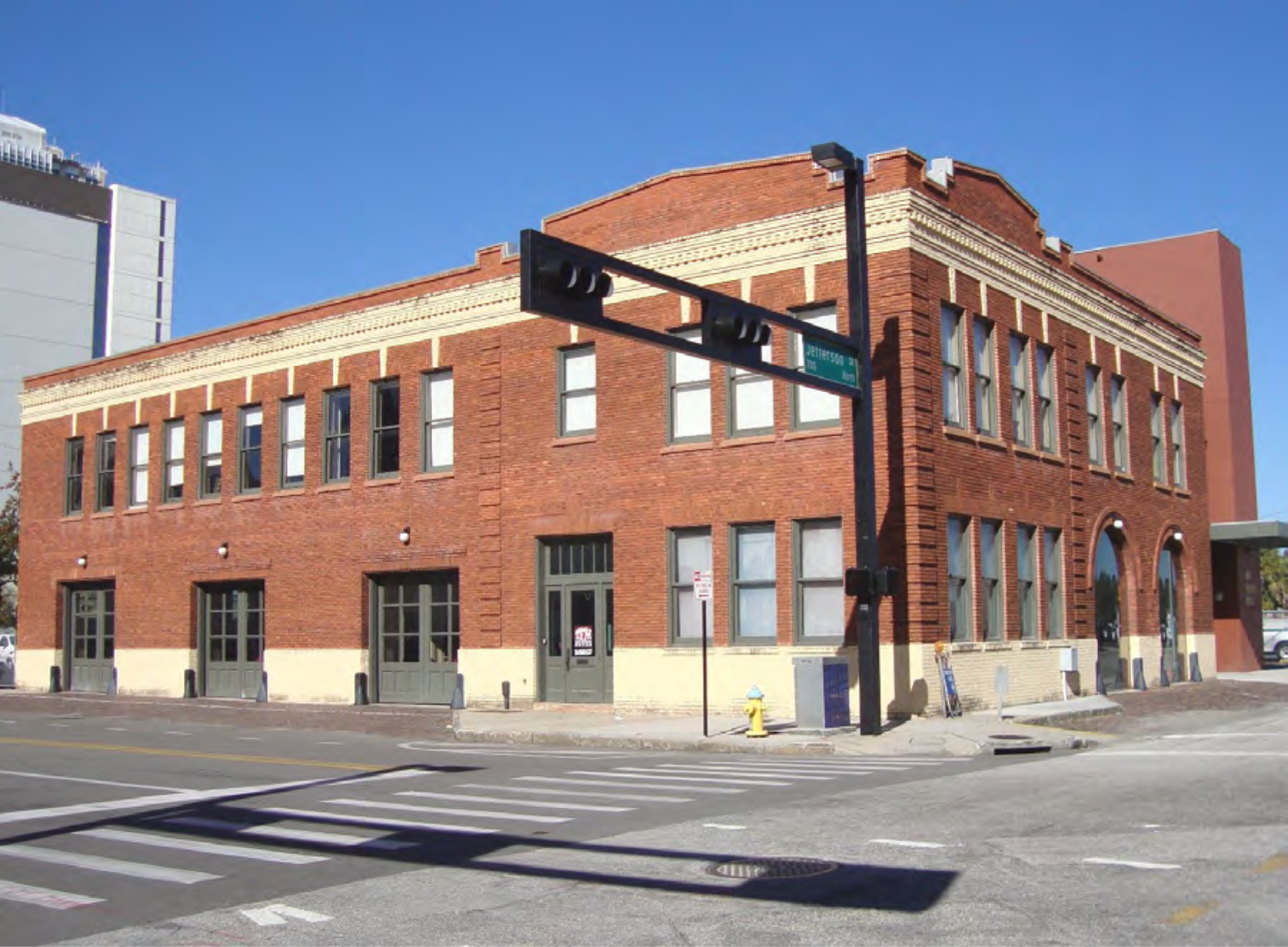 Historic brick building at a street corner with traffic signal, clear blue sky in the background.
