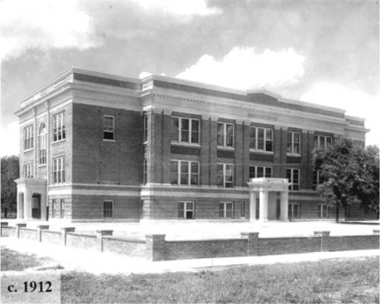 Black and white photo of a brick building from 1912, featuring large windows and a central entrance.