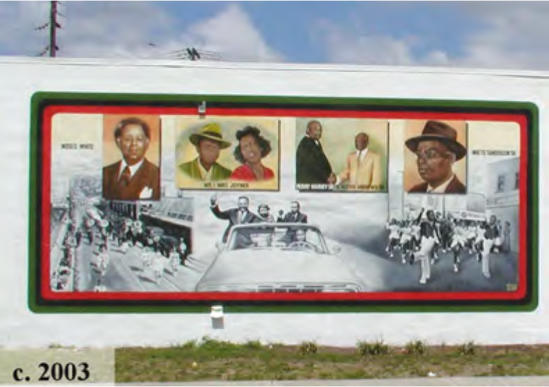 Mural featuring prominent figures, colorful portraits, and a historic car parade scene, created around 2003.