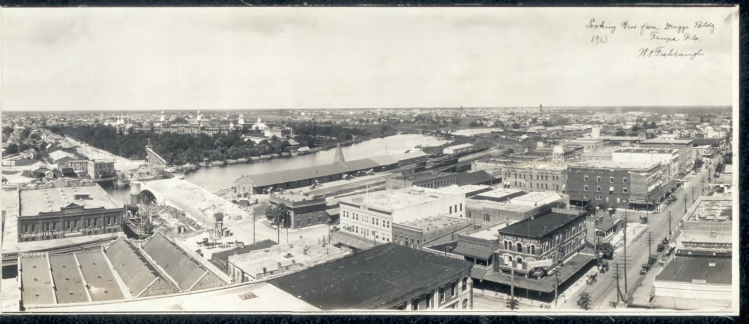 Historic panoramic view of a city in 1913, featuring buildings, a river, and construction activity.