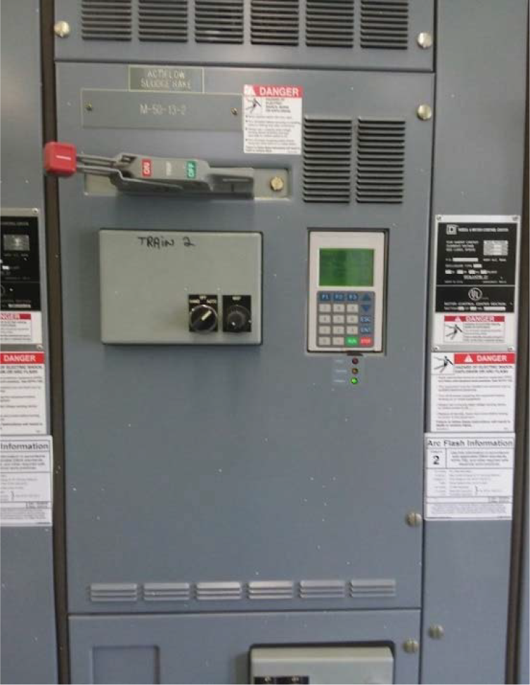Control panel with labels, switches, and a digital display, found in an industrial setting, warning signs present.