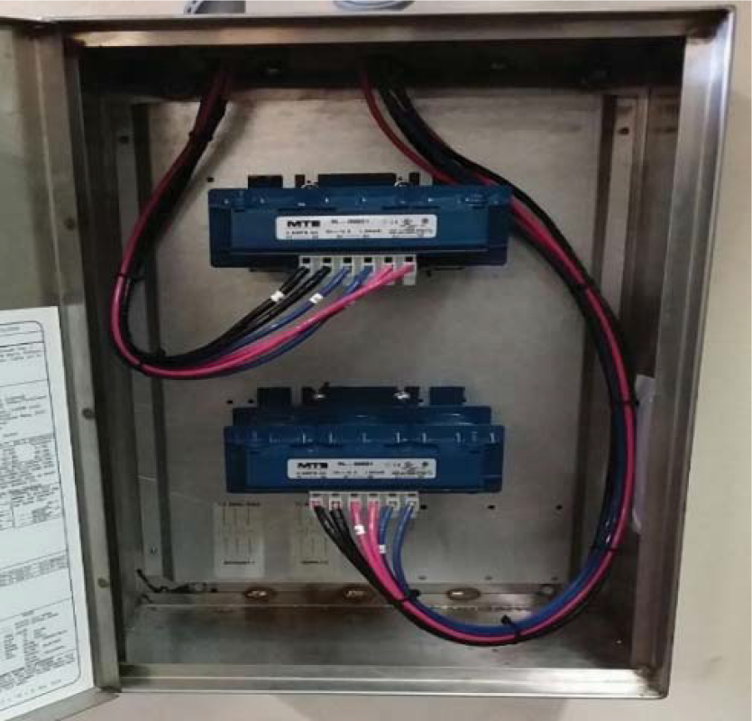 Close-up of a metal electrical enclosure containing two blue MTR units with multiple colored wires connected.