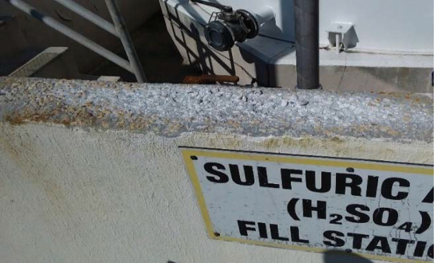 Close-up of a metal structure showing corrosion, with a sign indicating 'Sulfuric Acid (H2SO4) Fill Station' nearby.