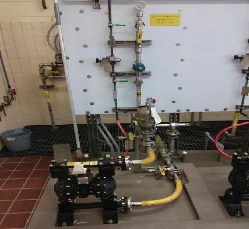 Industrial valve and piping system with various gauges and fittings in a tiled environment.