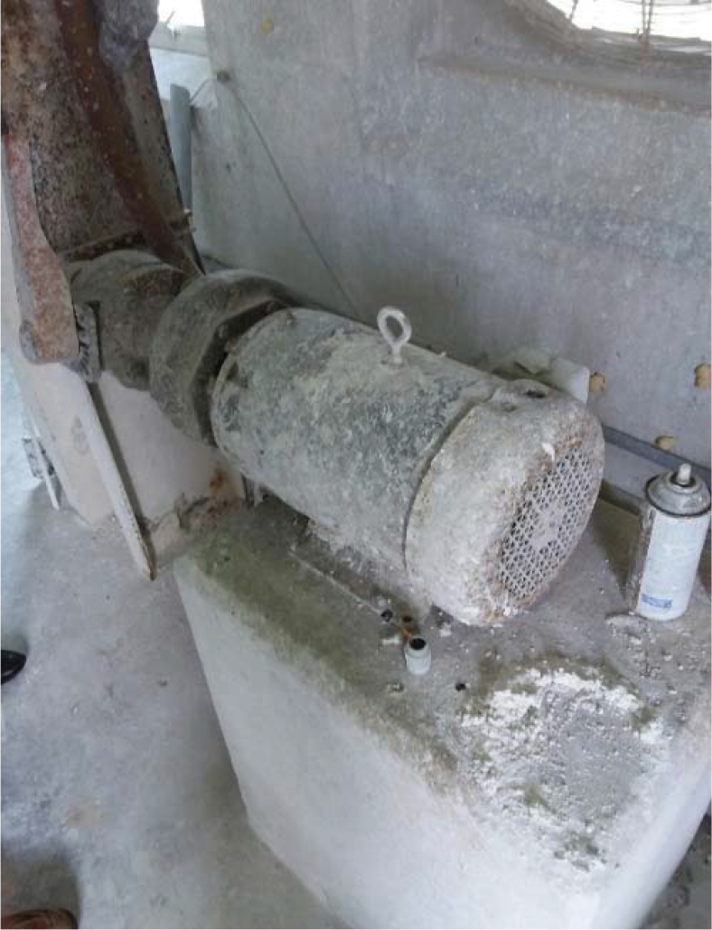 A dusty motor attached to a concrete base in an industrial setting, indicating possible neglect or disuse.