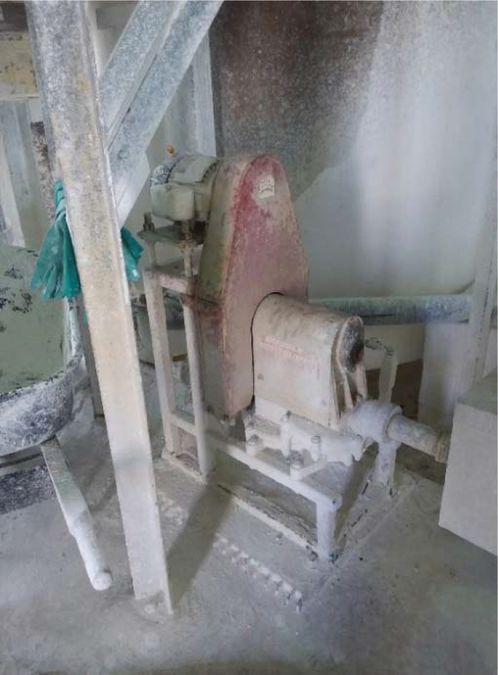 A dusty industrial machine with a motor, situated in a construction or manufacturing environment.