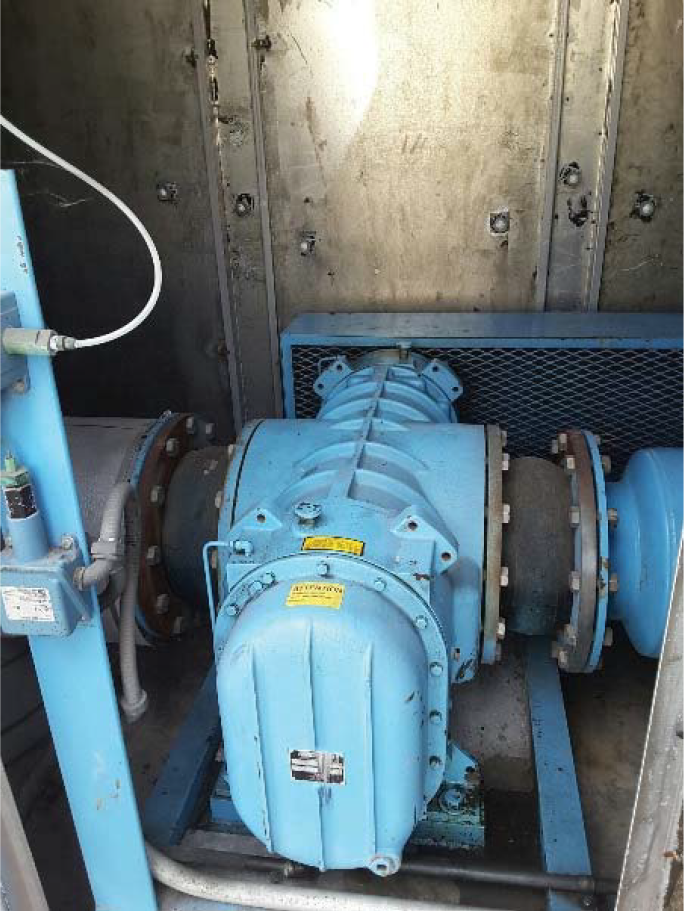 Industrial blue pump inside a metal enclosure, with pipes and electrical components visible.