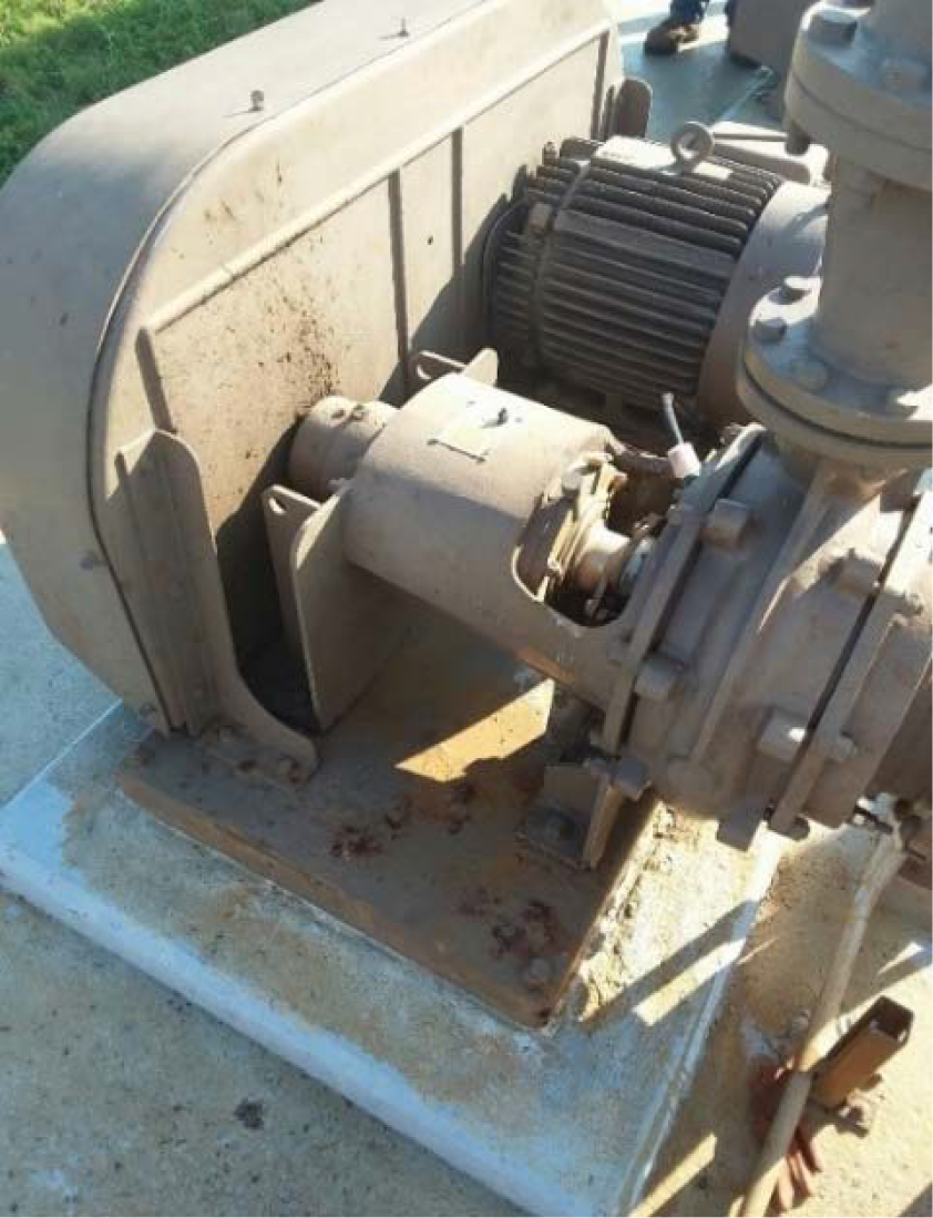 Close-up of a dirty industrial motor and pump assembly on a concrete surface.