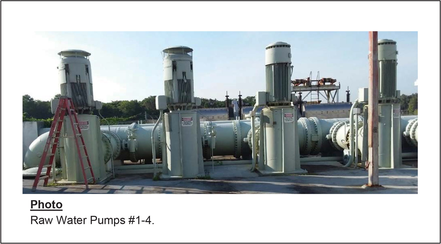 Four raw water pumps with large motors and pipes, positioned outdoors with a ladder nearby.