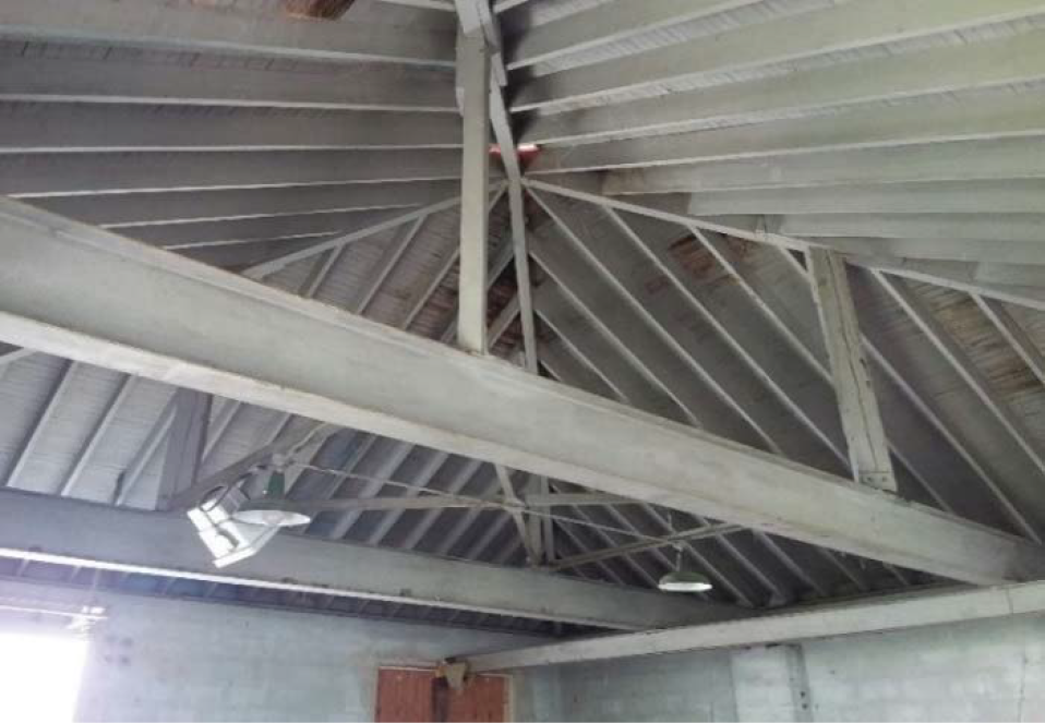 Interior view of a building showing a sloped roof with metal beams and wooden accents.