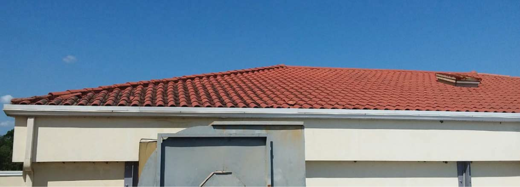 A red tiled roof of a building under a clear blue sky.