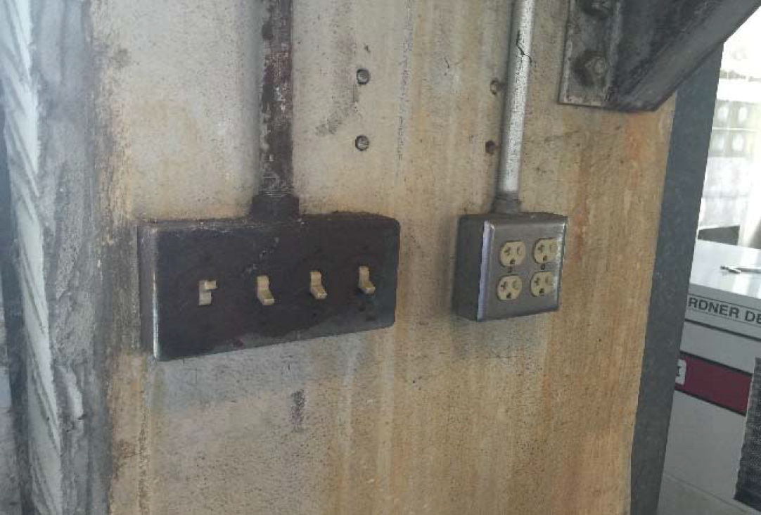 Two electrical outlets mounted on a wall, one with three sockets and the other with four sockets, showing signs of wear and rust.