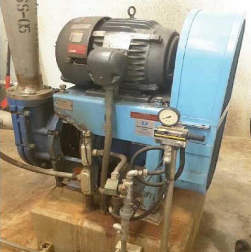 Industrial pump with electric motor and gauges mounted on a concrete base, connected to piping.
