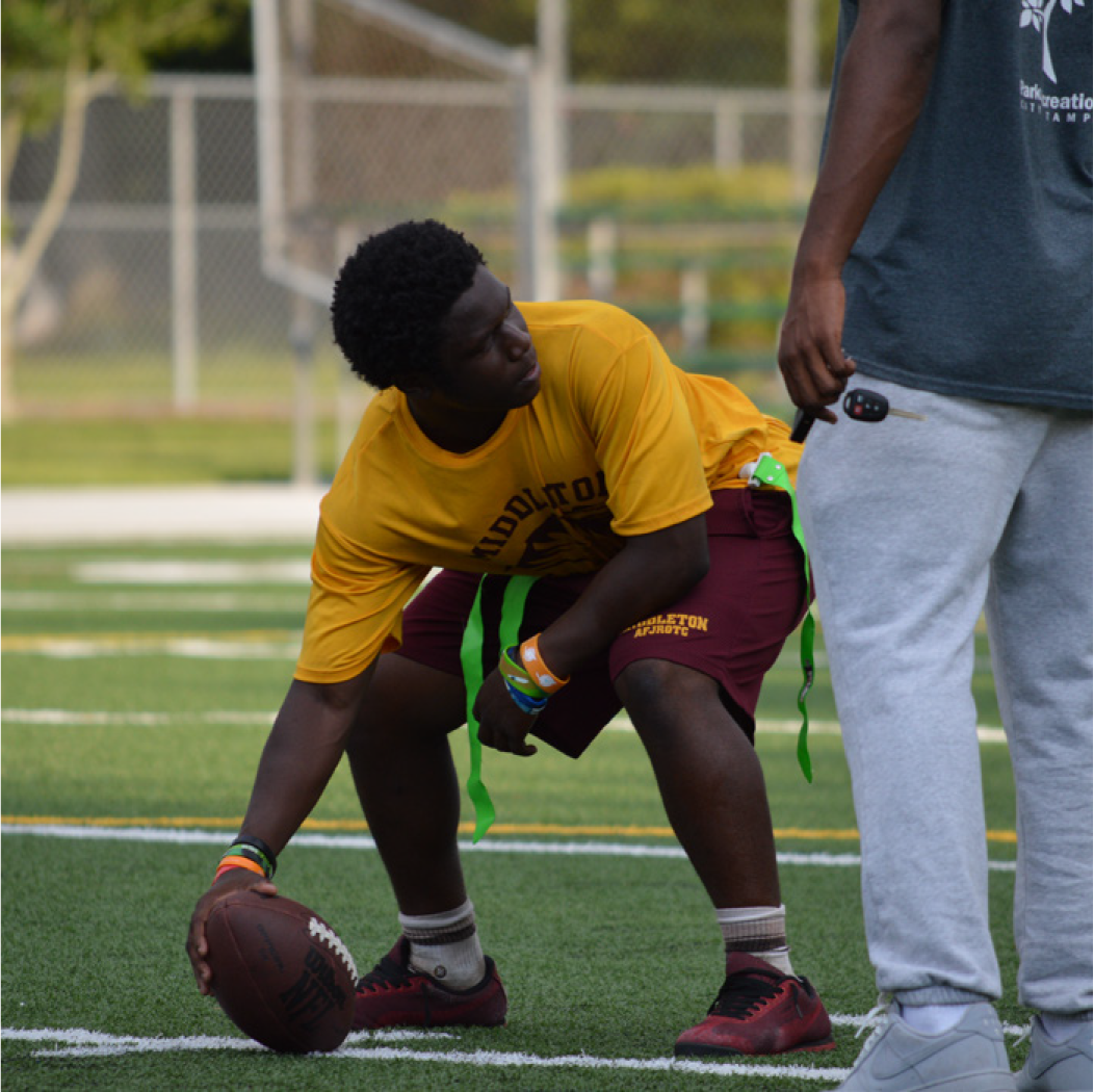 Young athlete preparing to throw a football during practice on a field.