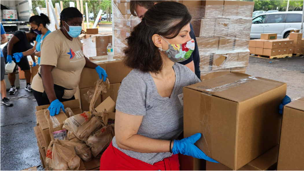 Volunteers organizing food boxes at a community food distribution site, wearing masks and gloves.