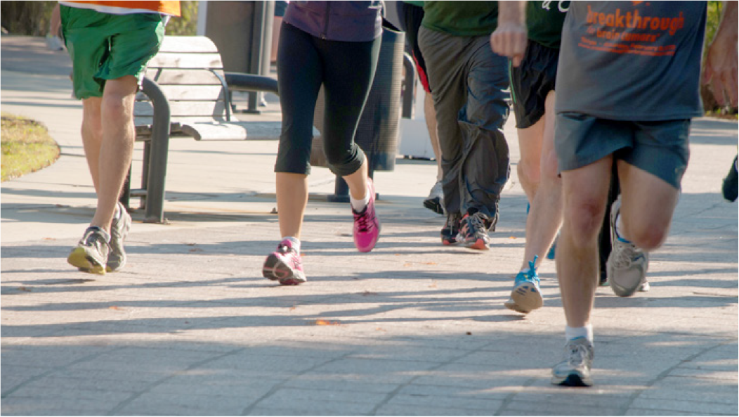 Group of runners' legs in motion on a paved path during a fitness event.