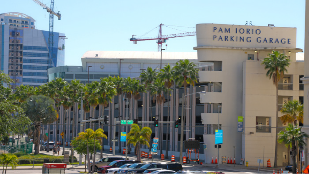 View of Pam Iorio Parking Garage surrounded by palm trees and construction sites in a sunny urban setting.