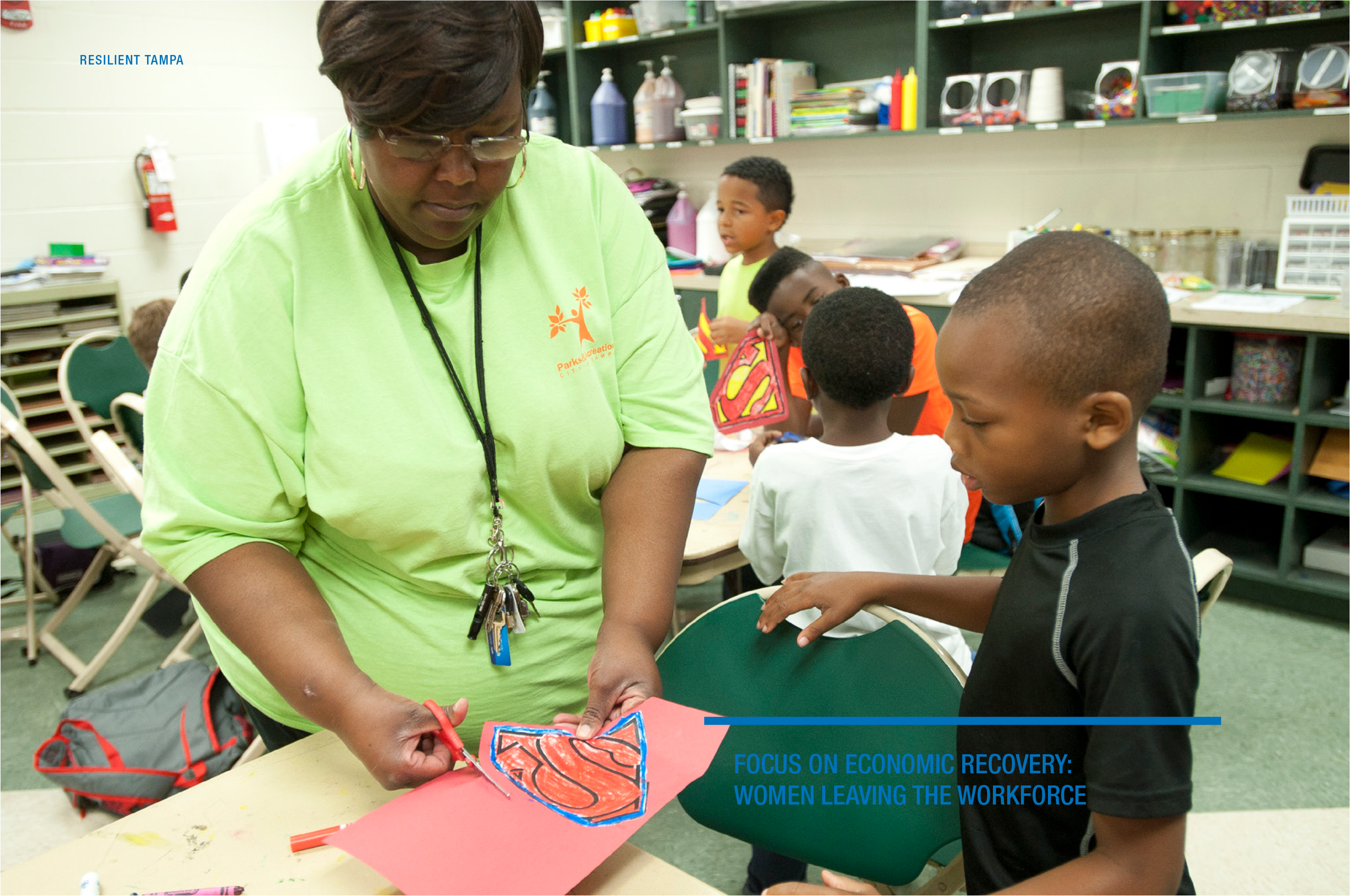 A woman assists children in an art activity in a classroom setting, focusing on economic recovery and workforce challenges.