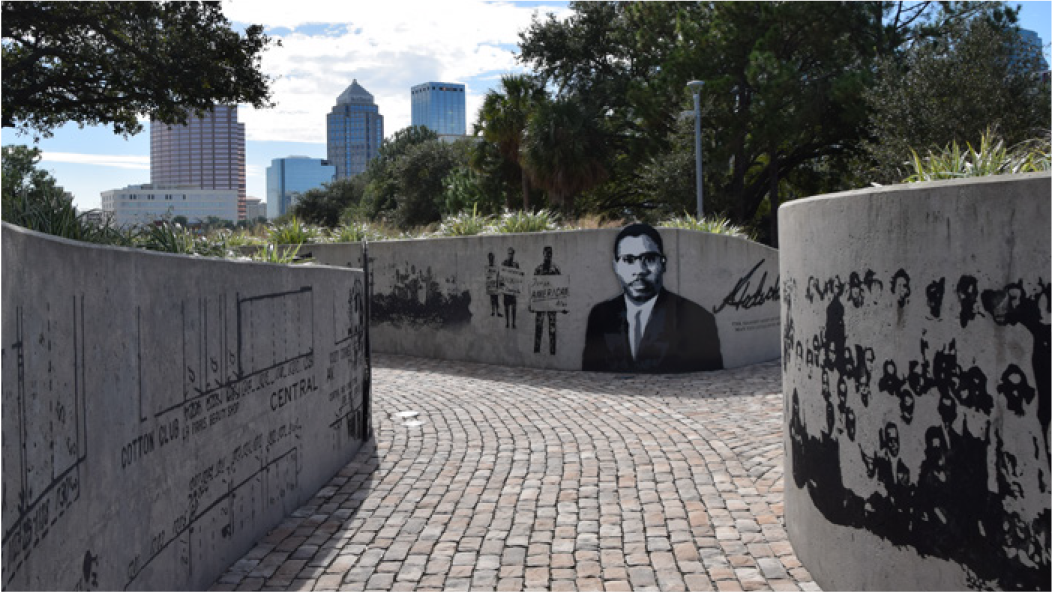 A winding walkway featuring black and white murals, with a city skyline in the background.
