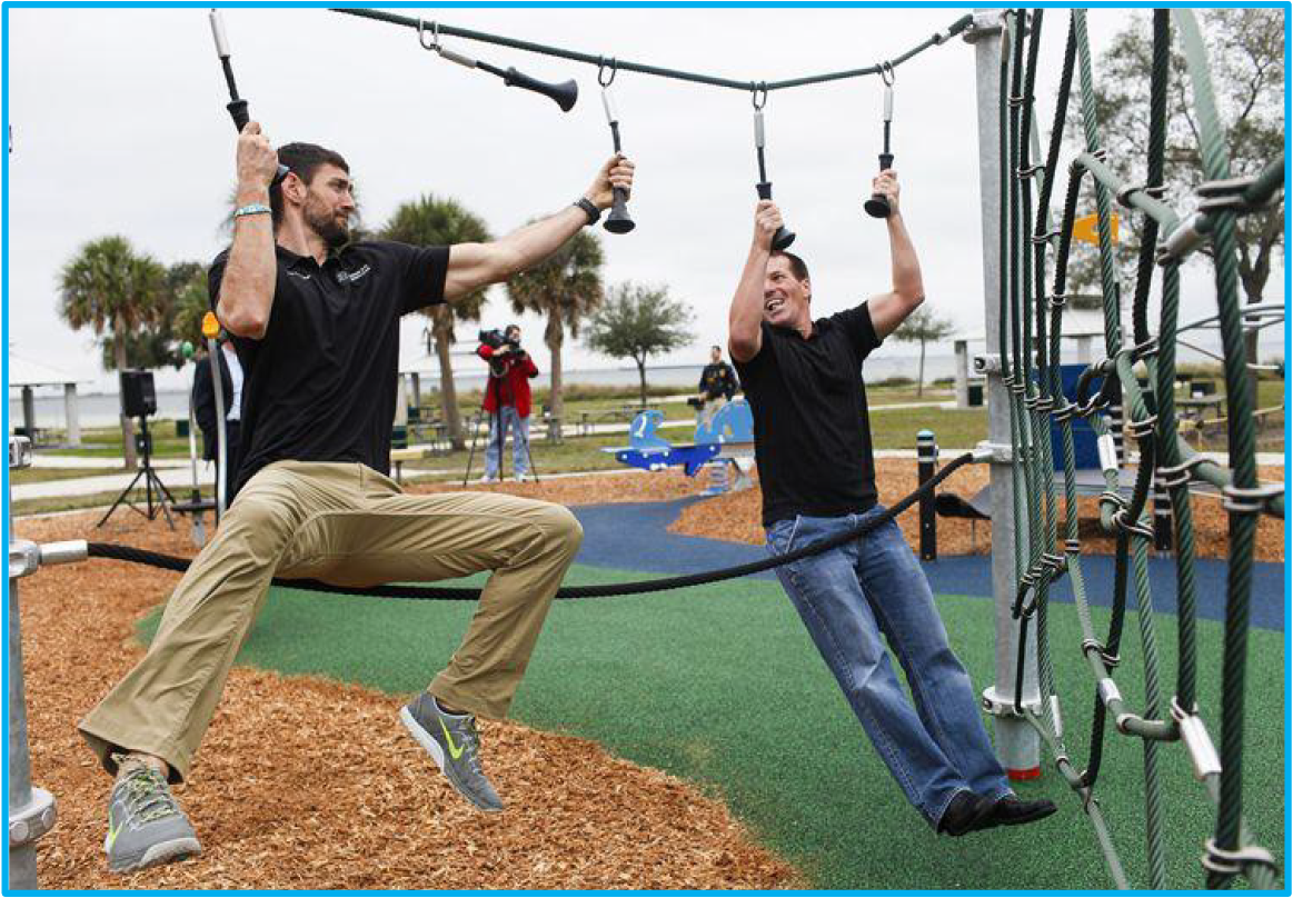 Two men swinging on a playground apparatus, enjoying an outdoor activity at a park.