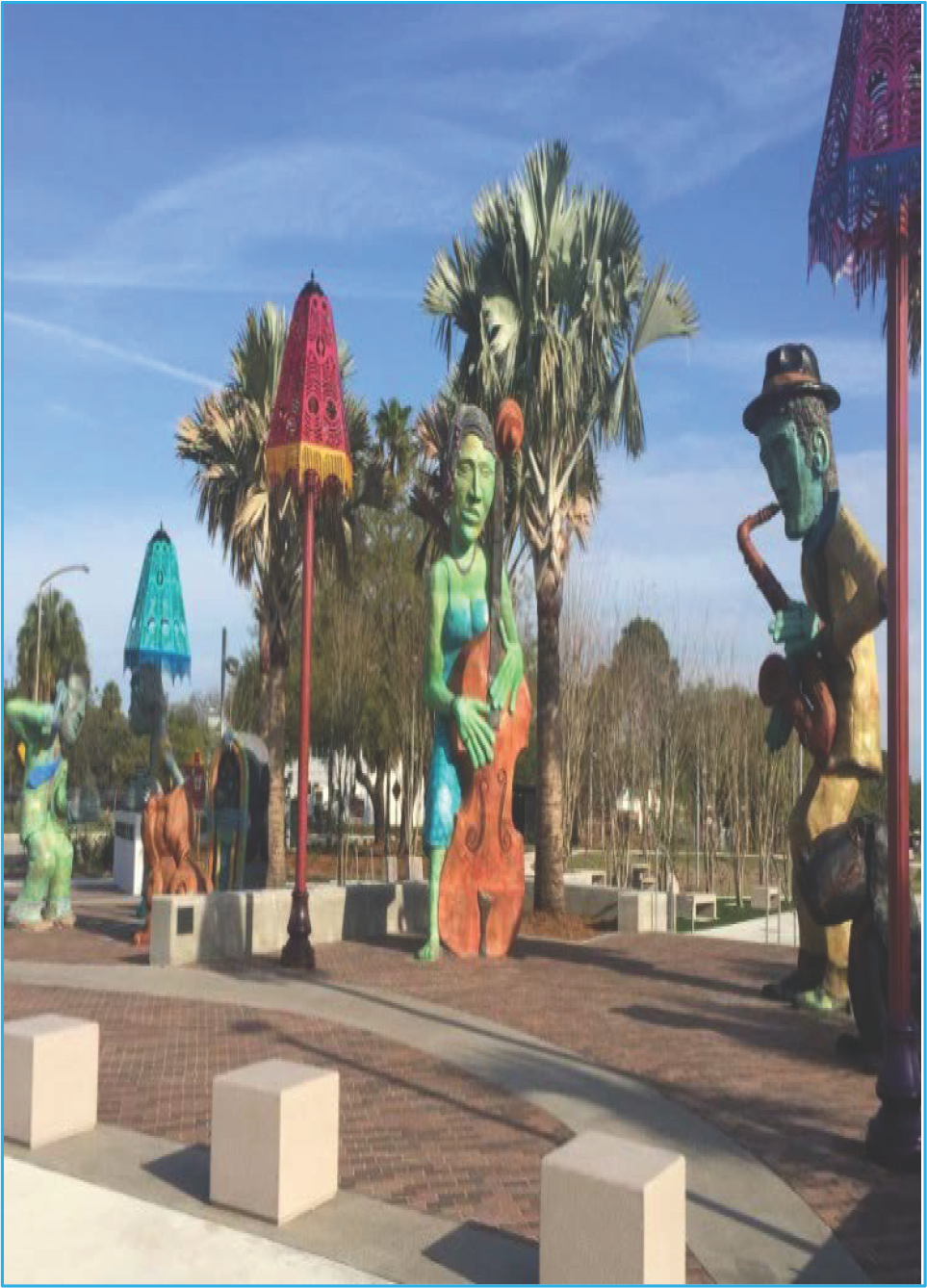 Colorful sculptures of musicians playing instruments surrounded by palm trees in an outdoor park setting.