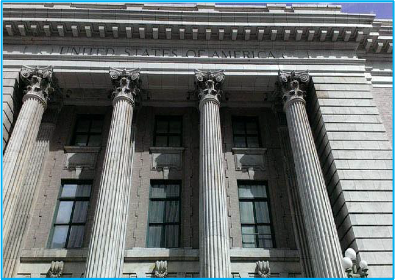 Facade of a historic building with large columns and windows, inscribed with 'THE UNITED STATES OF AMERICA' above.