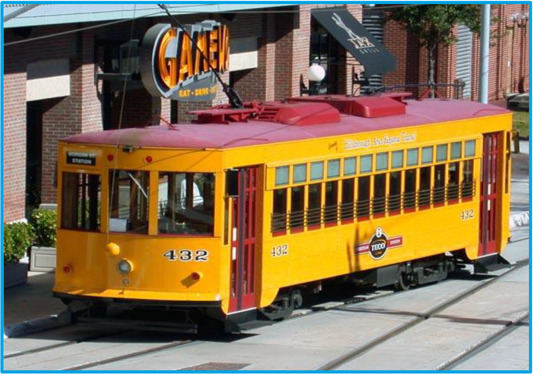 A yellow streetcar labeled '432' parked near a restaurant, set against a brick building backdrop.