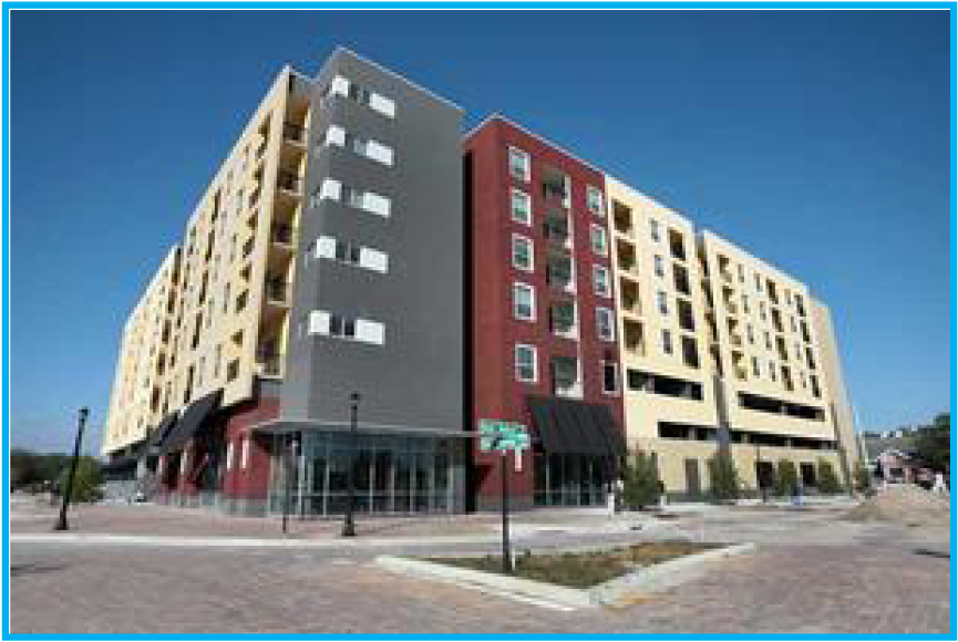 A modern, multi-story building with a mix of yellow, red, and gray facades under a clear blue sky.